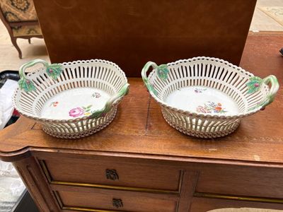 une paire de paniers anciens peints à la main posés sur une commode ancienne