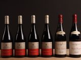 six bouteilles de vin rouge alignées sur une table en bois