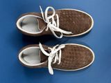 pair of brown shoes with white laces on a blue surface