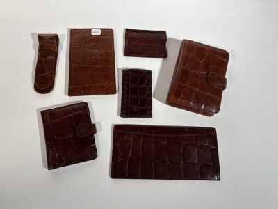 several pieces of brown alligator skin wallets on a white surface