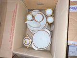 a box full of white and gold plates and bowls