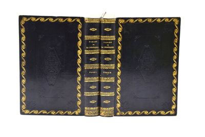 Deux livres noirs aux tranches dorées sont ouverts sur une surface blanche