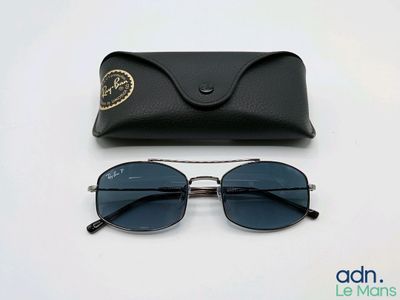Des lunettes de soleil Ray-Ban et leur étui posés sur une surface blanche