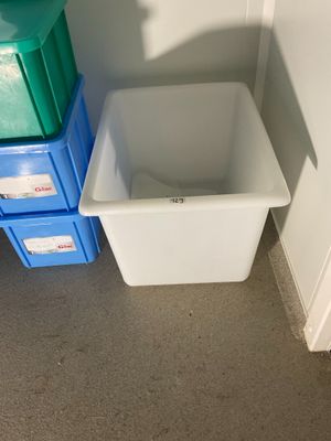 une poubelle blanche à côté d'un conteneur bleu et vert