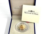 a close up of a gold coin in a box on a white surface