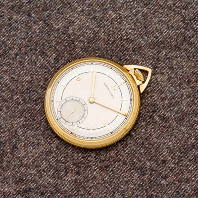 une montre de poche en or posée sur un tapis marron