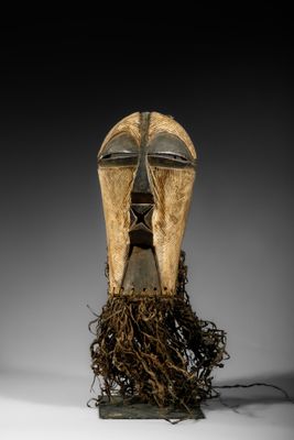 un masque en bois avec de longs cheveux et un visage sculpté dans le bois