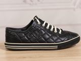 a black leather sneaker with white laces on a wooden table