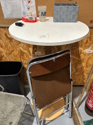 une petite table avec une chaise et une poubelle dans un coin