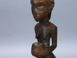 une petite statue en bois représentant une femme tenant un bol