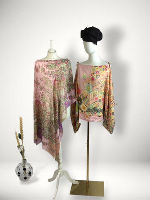 two women ' s scarves on a mannequin stand next to a vase of flowers