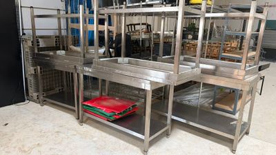 a kitchen with a lot of stainless steel shelvings on the floor