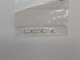 un petit sachet de perles argentées posé sur une surface blanche