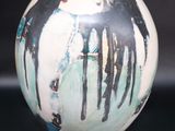 a white and black vase with a painting on it