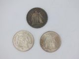 three different types of silver coins on a white surface