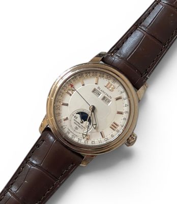 gros plan d'une montre sur une surface blanche avec un bracelet marron