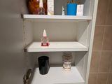 une étagère sur laquelle sont posés de nombreux objets dans la salle de bains