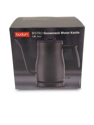 La boîte d'une cafetière noire est ouverte sur une surface blanche.