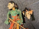 a doll with a stick next to other dolls on the floor