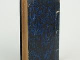 an old book with a blue cover sitting on top of a white surface