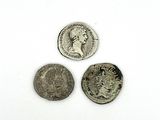 trois pièces de monnaie romaines antiques posées sur une surface blanche, sur fond blanc