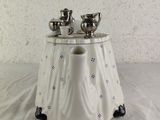 a white table with two silver teapots on it