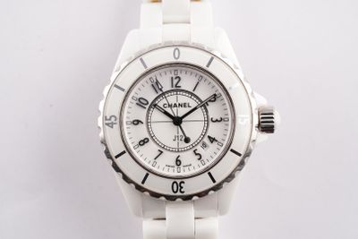 La montre est blanche et comporte des chiffres noirs.