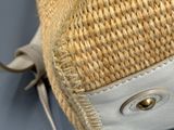un sac en paille avec une anse en cuir sur fond bleu
