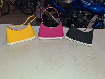 three purses sitting on a table next to a motorcycle