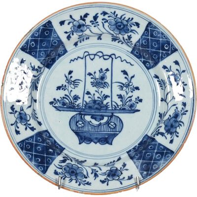 une assiette bleue et blanche sur laquelle est représenté un panier de fleurs