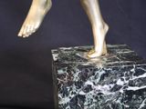 bronze statue of a boy on a marble base holding a tennis racket