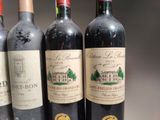 three bottles of red wine are lined up on a table