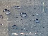 reflection of a building in a window with water droplets on the glass