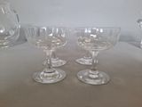 three wine glasses sitting on a table with a pitcher in the background