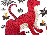 a red and black cat sitting on a white table cloth