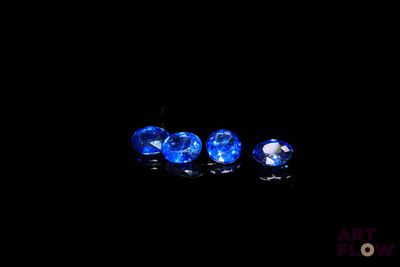 trois saphirs bleus sur une surface noire dans l'obscurité