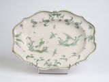 a green and white plate on a stand on a white surface