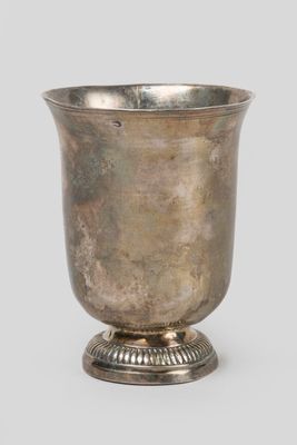 an antique silver cup on a pedestal on a gray background