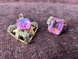 une paire de boucles d'oreilles roses et dorées posées sur un fond violet