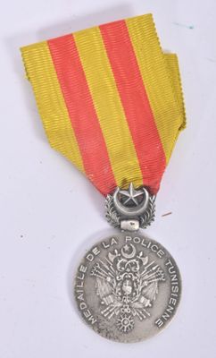 an old medal with a red and yellow ribbon on a white surface
