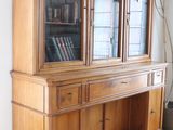 a wooden china cabinet with a glass door in a living room