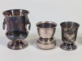 three silver vases sitting next to each other on a table