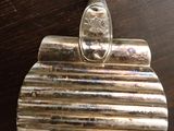 un porte-monnaie plaqué argent posé sur une table en bois, muni d'une poignée en métal