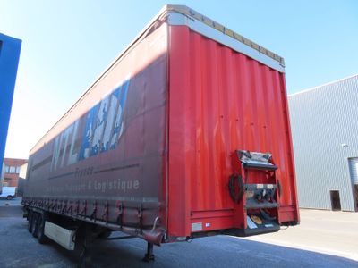 un semi-remorque rouge garé devant un immeuble
