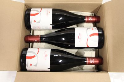 three bottles of wine in a cardboard box on a table