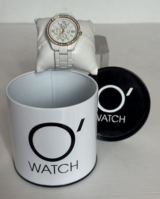 une montre posée dans une tasse à café à côté d'un coffret à montres
