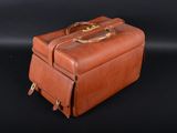 brown leather suitcase sitting on a black surface with a black background