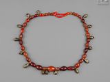 un collier de perles rouges et dorées orné de clochettes