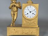 une horloge en or surmontée d'une statuette représentant un Cupidon