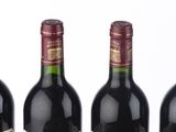 three bottles of red wine are lined up on a white surface
